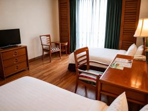 a hotel room with two beds and a desk at Sabah Oriental Hotel in Kota Kinabalu