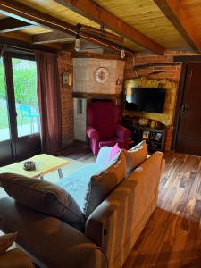 a living room with a couch and a tv at Dunja Cabin - Forest House with Pool in Banja Luka