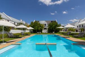 a large swimming pool with chairs and umbrellas at Winelands Golf Lodges 2 in Stellenbosch