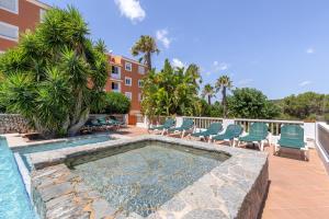 a swimming pool with chairs and a building at Son Bou Pool and Sea in Son Bou