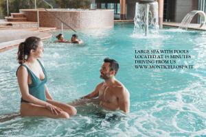 a man and a woman sitting in a swimming pool at Villa Galimberti Maison De Charme in Osnago