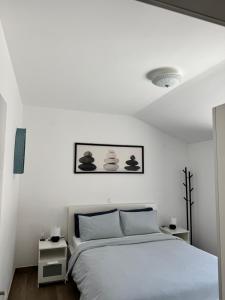 a white bedroom with a bed and two night stands at Seafront Apartment Strunjan in Strunjan