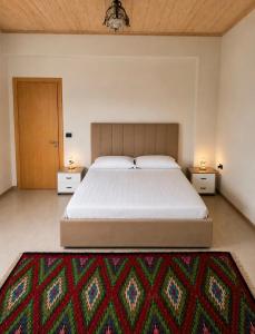 a bedroom with a large bed with two night stands at Versailles Rooms in Dukati i Ri