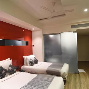 a bedroom with two beds and a red wall at VITS Sharanam, Thane in Thane