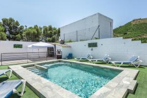 a swimming pool with two chairs and a building at Casa Villazo 1 in Málaga