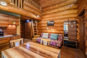 a log cabin living room with a table and a couch at Holiday Home Happiness in Hočko Pohorje