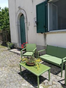 two green benches and a table with flowers on it at Casa Bea in Castiglione