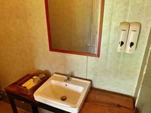 a bathroom with a sink and a mirror at Cow Barn Cafe and Lodge Preah Vihear in Phumĭ Nhông