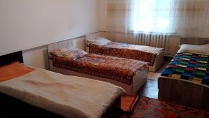 a room with three beds and a window at House Ali in Chirganak