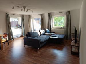 a living room with a blue couch and two windows at Lodge Ehrenberg in Ehenbichl