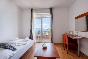 a bedroom with a bed and a desk and a table at Villa Sunce Beachfront in Podgora