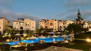 a view of a resort with a pool and umbrellas at Sea View 4Bedroom Villa wz Jacuzzi Mountain View Ras Elhikma in Ras Elhekma