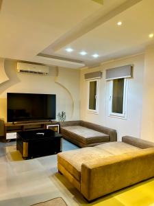 a living room with two couches and a flat screen tv at Sea View 4Bedroom Villa wz Jacuzzi Mountain View Ras Elhikma in Ras Elhekma