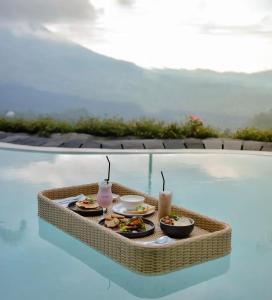 Caldera Hotel & Restaurant في Kintamani: صينية طعام موضوعة فوق حوض سباحة