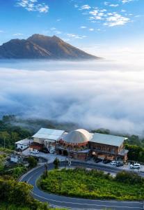 Caldera Hotel & Restaurant في Kintamani: منظر لمبنى مع جبل مغطى بالضباب