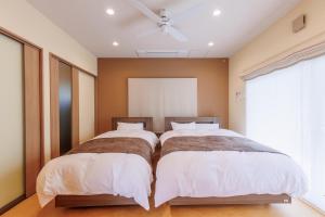 a bedroom with two beds and a ceiling fan at ヴィラ倉橋 in Kure