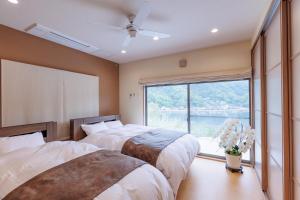 two beds in a room with a large window at ヴィラ倉橋 in Kure
