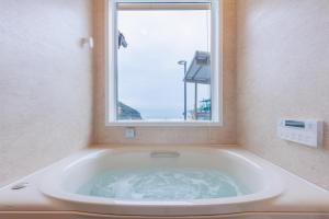 a bath tub in a bathroom with a window at ヴィラ倉橋 in Kure