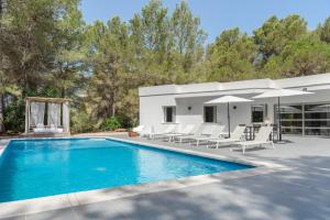 a pool with chairs and umbrellas next to a house at Can Drago in Ibiza Town