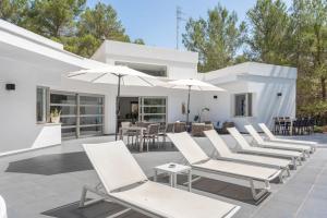 a row of white chairs and umbrellas on a patio at Can Drago in Ibiza Town