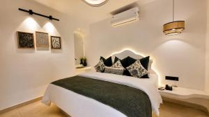 a white bedroom with a bed with black pillows at White Coco Luxury Villas, Private Pool, North Goa in Baga +28 photos