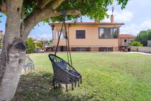 a swing hanging from a tree in a yard at Lola House tra Alghero e Stintino in Palmadula