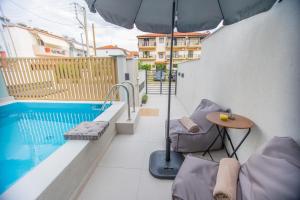 a balcony with a table and an umbrella and a pool at iMa-Ge Luxury in Nea Vrasna