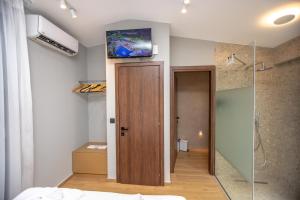 a bathroom with a shower and a television on the wall at iMa-Ge Luxury in Nea Vrasna