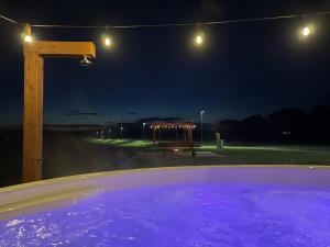 a hot tub at night with a bench and lights at Apartamenty Agro Roś in Pisz