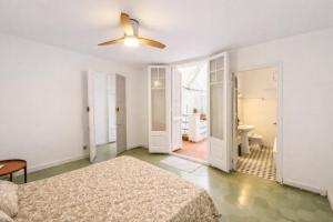 a white bedroom with a bed and a ceiling fan at La Casa de la Punta in San Pol de Mar