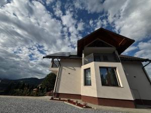 a small house with a cloudy sky in the background at VILA DAVELY in Câmpulung Moldovenesc