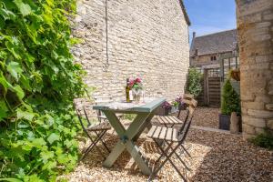 a table and chairs in a garden with a brick wall at Cozy Cotswold Burford Cottage in Burford