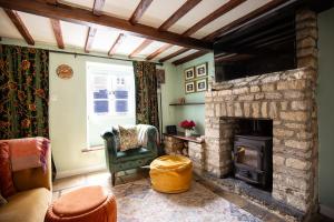 a living room with a stone fireplace with a television at Cozy Cotswold Burford Cottage in Burford