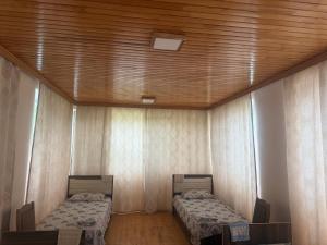 two beds in a room with a wooden ceiling at Cozy house in Sheki