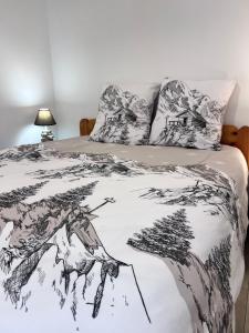 a bed with a black and white blanket and pillows at Résidence La Mayt in Vars