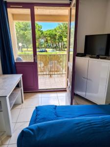 a living room with a blue couch and a sliding glass door at Appartement cosy à Gruissan, piscine partagée, 25 m² in Gruissan