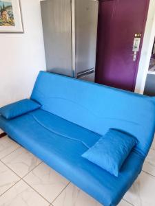 a blue couch in a room with a refrigerator at Appartement cosy à Gruissan, piscine partagée, 25 m² in Gruissan