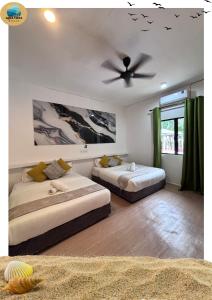 a bedroom with two beds and a ceiling fan at Aqua Vista Merang in Kampung Merang