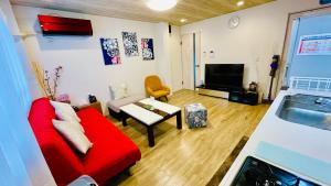a living room with a red couch and a tv at Nagoya Minpaku, KANAYAMA BASE in Mutsunochō