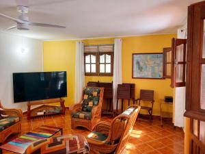 a living room with a flat screen tv and chairs at Maison charmante à Pointe Noire, vue montagne, jardin privé in Pointe-Noire