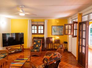 a living room with yellow walls and a flat screen tv at Maison charmante à Pointe Noire, vue montagne, jardin privé in Pointe-Noire