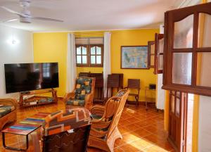a living room filled with furniture and a flat screen tv at Maison charmante à Pointe Noire, vue montagne, jardin privé in Pointe-Noire