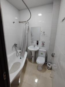 a white bathroom with a toilet and a sink at KAMIR Guest House in Bukhara