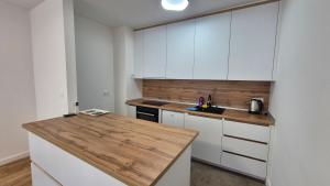 a kitchen with white cabinets and a wooden counter top at MyPlace apartmani 8 in Tuzla +6 photos
