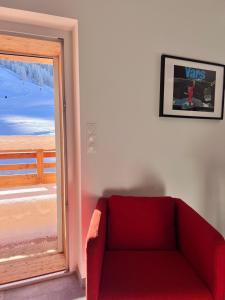 a red couch in a room with a window at Résidence La Mayt in Vars