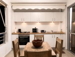 a kitchen with white cabinets and a wooden table and chairs at Studio charmant à La Trinité - Vue mer - 40 m² in La Trinité