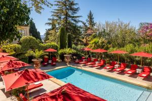 a swimming pool with red umbrellas and lounge chairs at Villa Gallici Hôtel & Spa in Aix-en-Provence