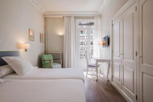 a hotel room with a bed and a desk and a window at Hotel Niza in San Sebastián