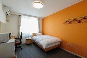 a bedroom with a bed and a desk and a window at kkrshirahamamihamasou in Shirahama
