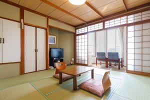a living room with a table and chairs and a tv at kkrshirahamamihamasou in Shirahama